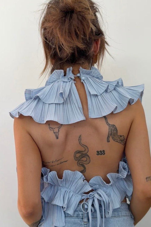 Person wearing a denim outfit with ruffled details on a plain background