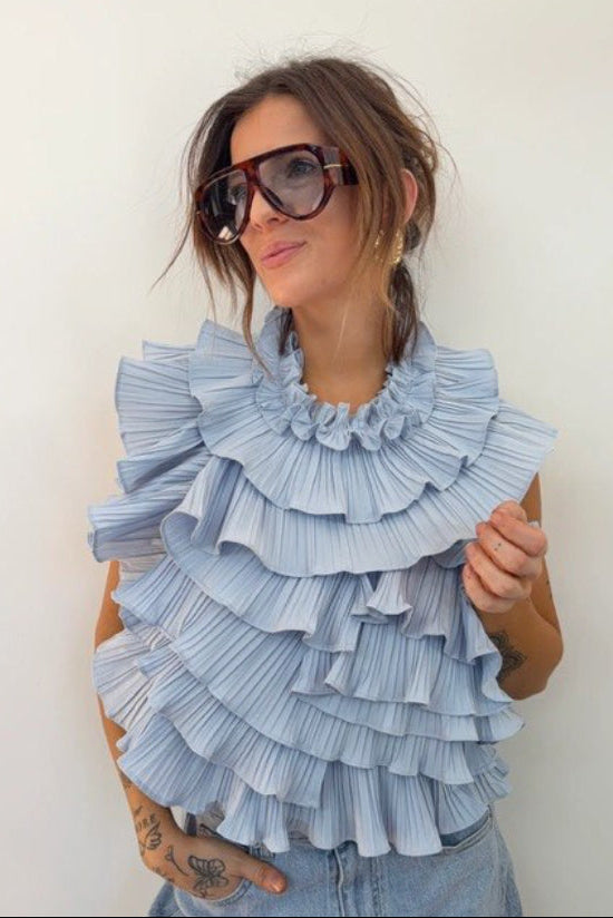 Woman wearing a blue ruffled top with 'Lovers' clothes' branding.