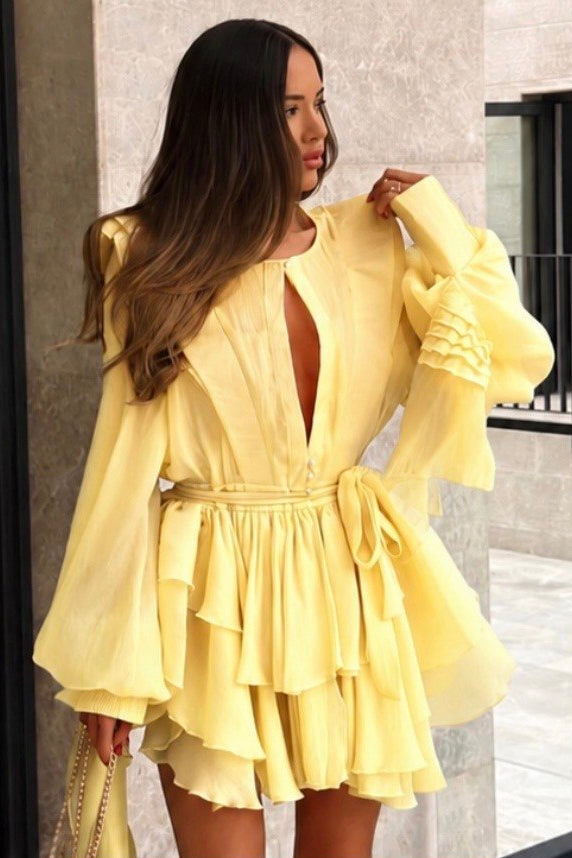 Woman wearing a yellow dress standing in front of a building.