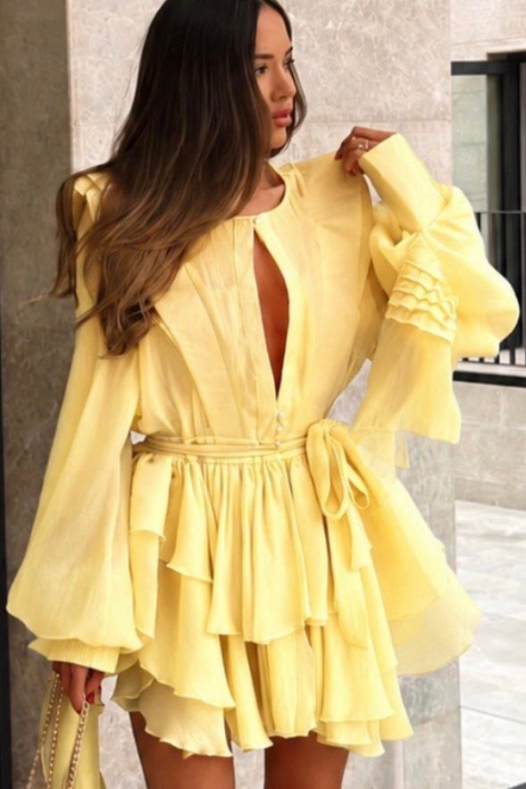 Woman wearing a yellow dress standing in front of a building.